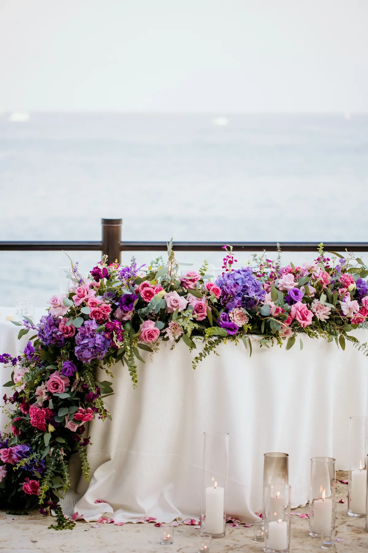 A low sweetheart-table garland running from palest lilac to deep plum, with orchids trailing onto the linen.
